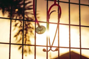 A stethoscope hangs on a mesh wall before a setting sun